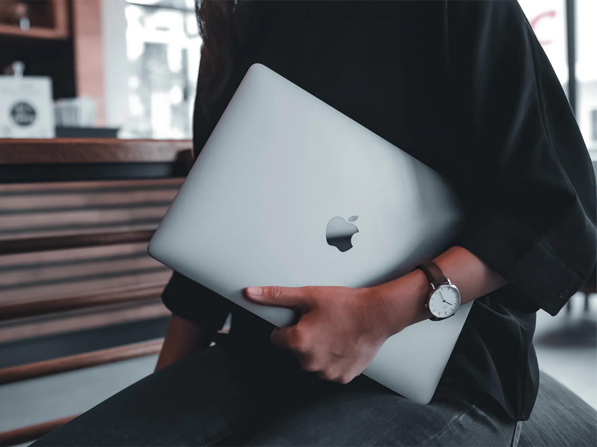 Developer at LXE Digital holding a MacBook in a relaxed workspace, ready to build custom web and mobile applications