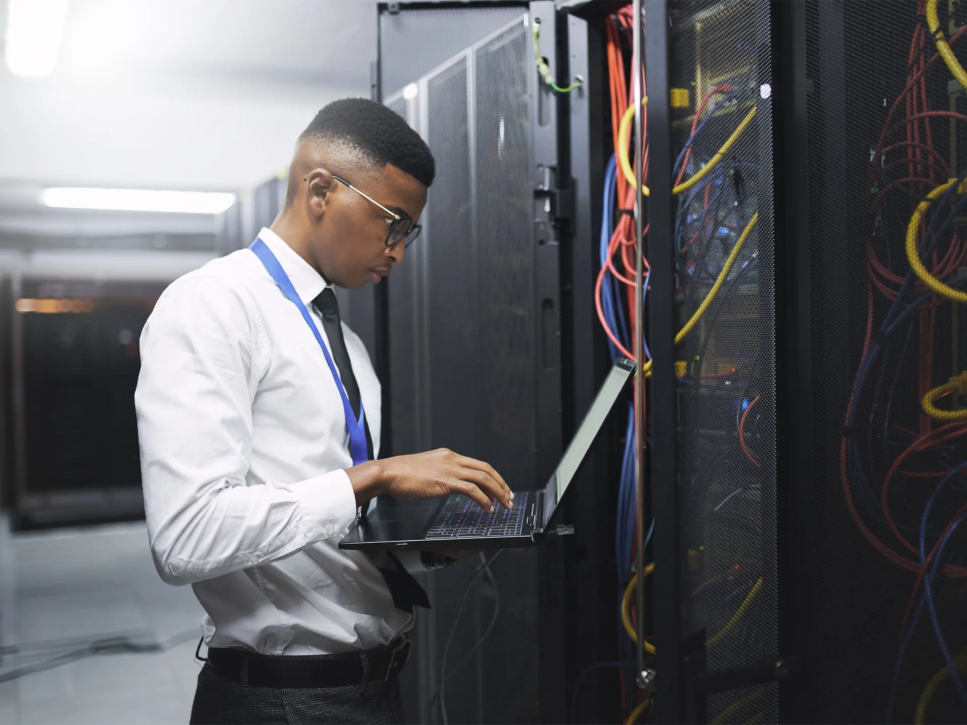 Technician using a laptop in a server room during a commercial hardware installation led by LXE Digital for a healthcare facility communications upgrade